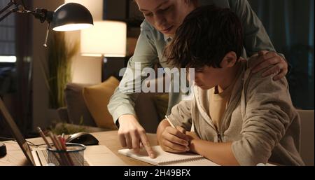 Sorella premurosa che aiuta suo fratello più giovane con i compiti a scuola Foto Stock