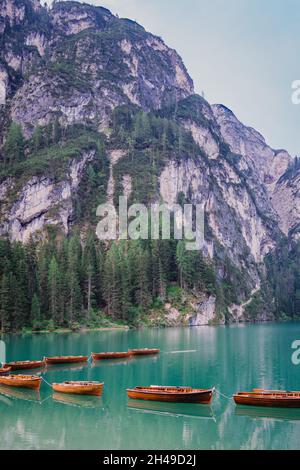 Colpo verticale di barche su un lago ghiacciato vicino a scogliere affilate in Italia Foto Stock