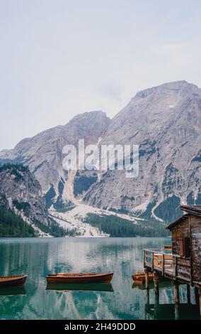 Colpo verticale di barche su un lago ghiacciato vicino a scogliere innevate in Italia Foto Stock