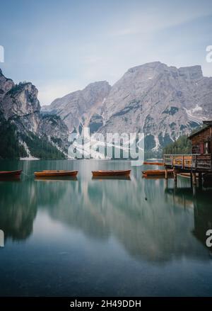 Colpo verticale di barche su un lago ghiacciato vicino a scogliere innevate in Italia Foto Stock