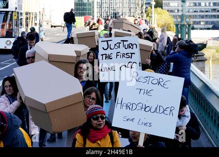 I dimostranti che protestano contro le autostrade intelligenti marciano con le casse attraverso il Ponte di Westminster fino a Piazza del Parlamento a Londra. Data foto: Lunedì 1 novembre 2021. Foto Stock