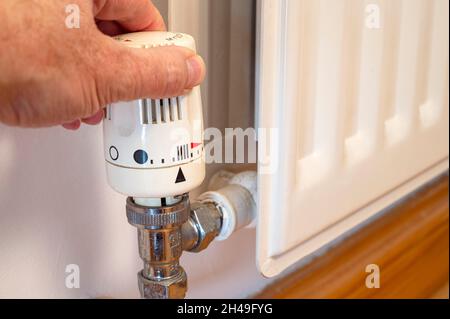 Mano dell'uomo che regola la temperatura di un radiatore Foto Stock