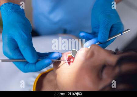 Dentista caucasico maschile che esamina i denti di una paziente femminile in clinica dentale moderna Foto Stock