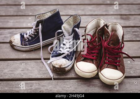 Primo piano ad angolo alto di tela blu sporca da coppia rossa di nuove scarpe sul pavimento Foto Stock