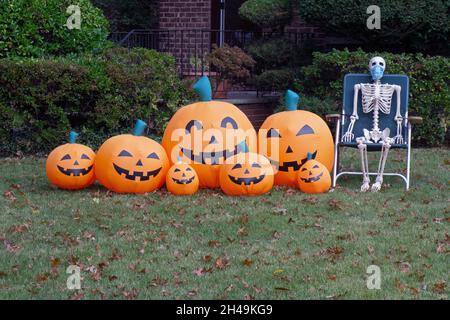 Le zucche sorridenti e una maschera che indossa lo scheletro decorano un prato anteriore per Halloween. A Queens, New York. Foto Stock