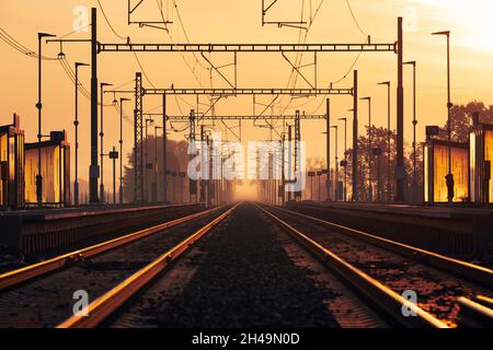 Ferrovia all'alba d'oro. Prospettiva decrescente di due binari ferroviari vuoti nella stazione. Foto Stock