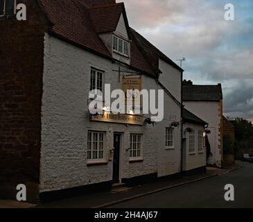 Il pub Three Horseshoes, una casa libera, nel villaggio rurale di Ecton nel Northamptonshire come le luci si accendono quando il crepuscolo arriva. Foto Stock