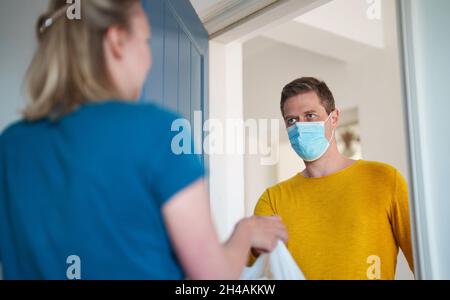 L'uomo mascherato trasporta il cibo durante la pandemia. Foto Stock