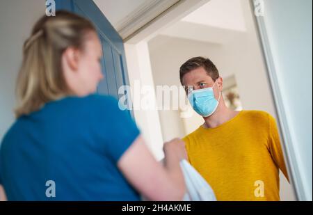 L'uomo mascherato trasporta il cibo durante la pandemia. Foto Stock