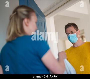 L'uomo mascherato trasporta il cibo durante la pandemia. Foto Stock