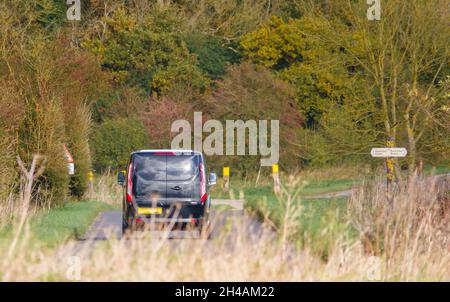 Black Ford Transit furgone personalizzato che guida attraverso la panoramica campagna autunnale Foto Stock