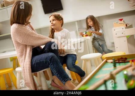 Insegnante di stanza dei bambini che parla alla ragazza piccola carina nell'asilo Foto Stock