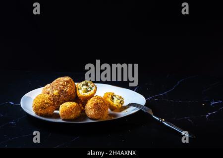 palle di formaggio con aglio e aneto all'interno per uno spuntino in un piatto su sfondo nero. Foto Stock