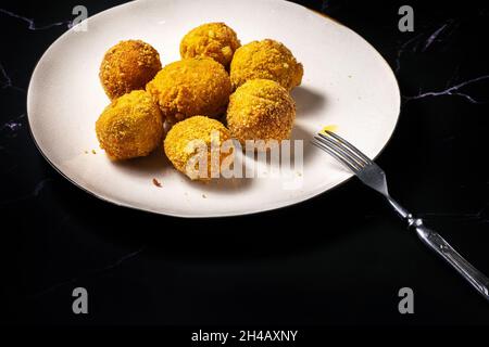 palle di formaggio con aglio e aneto all'interno per uno spuntino in un piatto su sfondo nero. Foto Stock