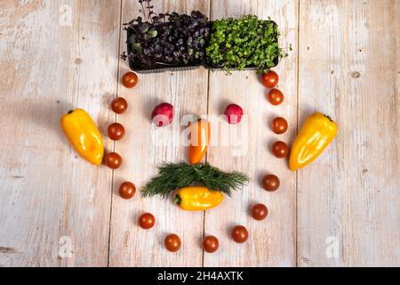 Il volto di un uomo fatto di verdure a fette su sfondo di legno. Foto Stock