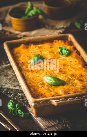 Pasta e formaggio cuocere con salsa di pomodoro e basilico su sfondo di legno, verticale Foto Stock