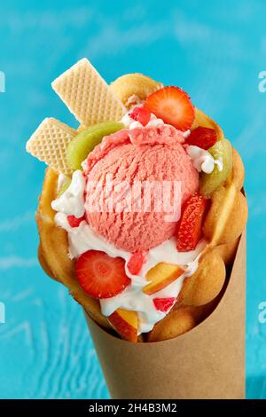 Gelato con waffle fai da te con frutta fresca e frutti di bosco su sfondo blu Foto Stock