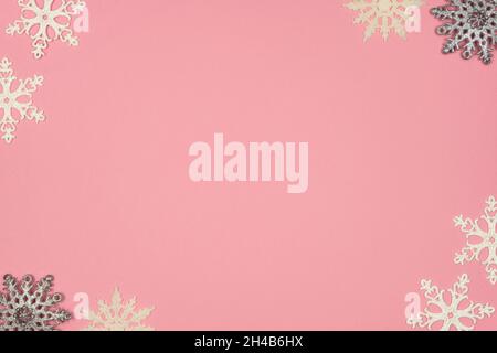 Concetto di Natale. Cornice in fiocchi di neve bianchi e grigi su sfondo rosa pastello. Vista dall'alto, spazio copia Foto Stock