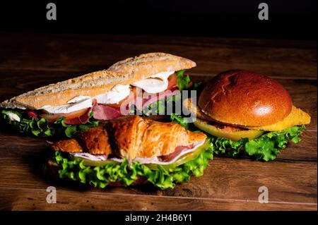 composizione di sandwich con salame e verdure su una superficie di legno Foto Stock