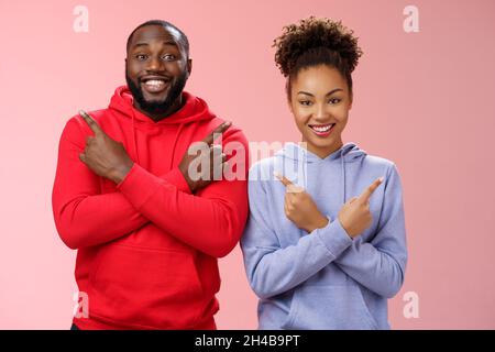 Affascinante coppia felice africano americano ragazzo ragazza muoversi insieme puntando diversi lati croce braccia petto sinistra destra sorridendo ampiamente Foto Stock