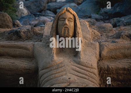 Scultura di Gesù fatta di sabbia sulla spiaggia di Maspalomas in Spagna Foto Stock