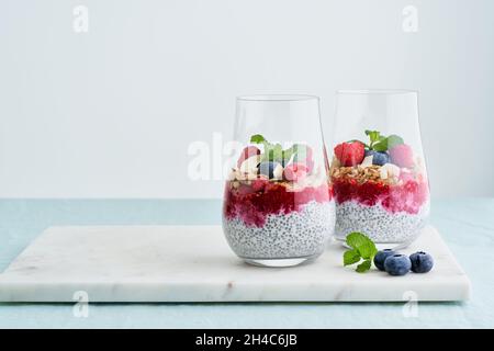 Semi freschi di chia, yogurt, lamponi, mirtilli, avena, menta di mandorle in vetro Foto Stock