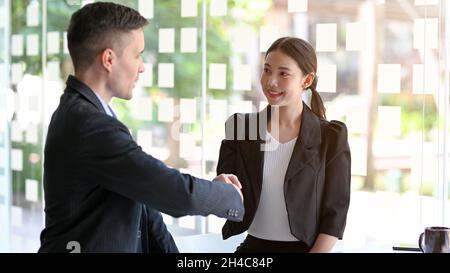 Mano di businessman caucasico che scuote con l'imprenditrice asiatica, partner commerciali diversi, affari, saluto. Foto Stock