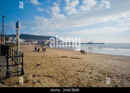 Spiaggia di Scarborough con persone anziane che si siedono al mattino presto Foto Stock