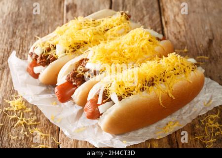 Hot dog al peperoncino americano con salsiccia di manzo, formaggio cheddar e cipolle da vicino su un vecchio sfondo di legno. Orizzontale Foto Stock
