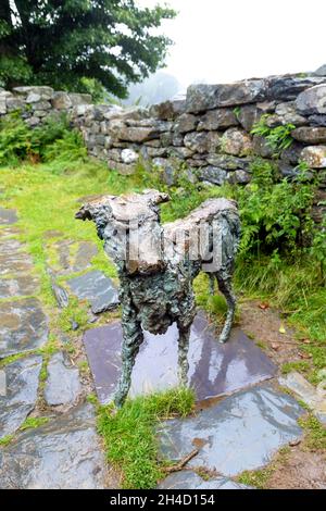 Scultura in bronzo del cane Gelert, posta in un cottage in rovina vicino alla tomba di Gelert, Beddgelert, Snowdonia National Park, Gwynedd, Galles, REGNO UNITO Foto Stock