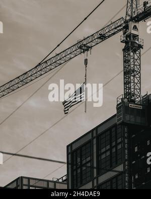 Scatto verticale in scala di grigi di una bandiera americana appesa alla gru Foto Stock