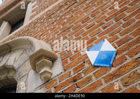 MECHELEN, BELGIO - 16 ottobre 2021: Un'immagine di un cartello "Beschermd Monument" su un edificio in mattoni classificato a Mechelen, Belgio Foto Stock