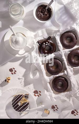 Ciambelle di cioccolato glassate e tazza di cappuccino su sfondo di pietra. Vista dall'alto. Composizione della disposizione piatta Foto Stock