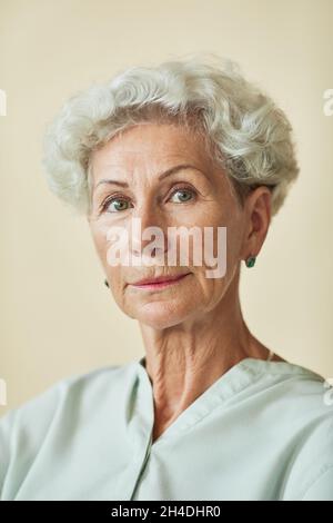 Ritratto verticale di elegante donna anziana che guarda la fotocamera su sfondo neutro Foto Stock