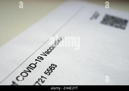 Iscrizione diagonale 'vaccination covid-19' in inglese su un modulo cartaceo rilasciato in Russia coloro che sono vaccinati contro il coronavirus su un bac sfocato Foto Stock