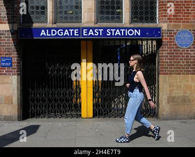 Una donna passa accanto a una stazione della metropolitana chiusa di Aldgate East a Londra est, mentre il Regno Unito continua a bloccarsi per contribuire a frenare la diffusione del coronavirus. Data foto: Venerdì 24 aprile 2020. Foto Stock