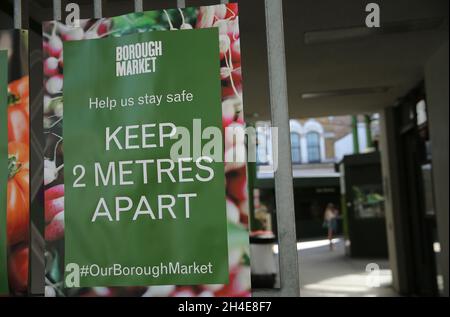 Un segnale che indica alle persone di aderire alle linee guida di distanziamento sociale, e di rimanere a due metri di distanza esposti in un ingresso al Borough Market di Londra, come i mercati all'aperto sono autorizzati a riaprire come parte di un più ampio allentamento delle restrizioni di blocco in Inghilterra. Data foto: Lunedì 1 giugno 2020. Foto Stock