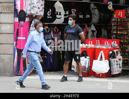 Gli acquirenti che indossano maschere per il viso passano davanti a un negozio di souvenir a Oxford Street, Londra, mentre i negozi non essenziali in Inghilterra aprono le loro porte ai clienti per la prima volta da quando le restrizioni di blocco del coronavirus sono state imposte a marzo. Data foto: Lunedì 15 giugno 2020. Foto Stock