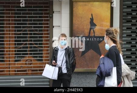 Le persone che indossano maschere protettive passeranno davanti a un vicino Victoria Palace Theatre, che non ha mostrato Hamilton dall'inizio del blocco del coronavirus a Londra. Data foto: Sabato 4 luglio 2020. Foto Stock