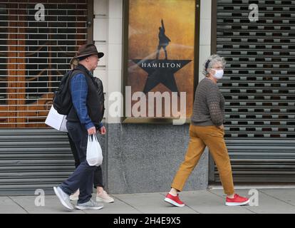 Le persone che indossano maschere protettive passeranno davanti a un vicino Victoria Palace Theatre, che non ha mostrato Hamilton dall'inizio del blocco del coronavirus a Londra. Data foto: Sabato 4 luglio 2020. Foto Stock