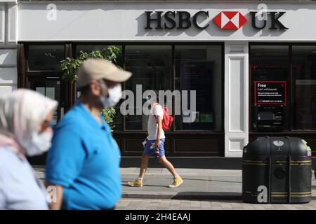 Le persone che indossano la copertura facciale passano una filiale britannica HSBC vicino a Covent Garden a Londra, in quanto la banca ha annunciato di accelerare i piani per tagliare 35,000 posti di lavoro in tutto il mondo dopo che la crisi del Covid-19 ha costretto la banca a mettere da parte altri 3,8 miliardi di dollari (2,9 miliardi di sterline) per coprire i debiti cattivi. Data foto: Venerdì 7 agosto 2020. Foto Stock