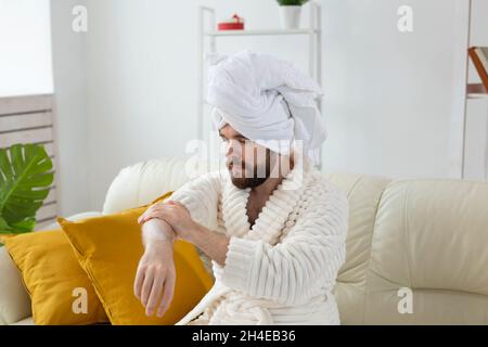 L'uomo bearded sfrega mano crema sulle sue mani. Spa, cura del corpo e della pelle per l'uomo concetto Foto Stock