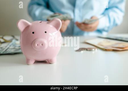 La donna d'affari conta le banconote in dollari in denaro. Risparmio di denaro per il piano futuro e il concetto di fondo di previdenza. Rosa piccante banca su tanle bianco Foto Stock