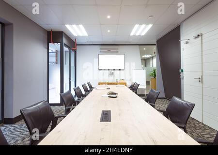 Interno di sala conferenze vuota con tv, scrivania e sedie in un ufficio moderno Foto Stock