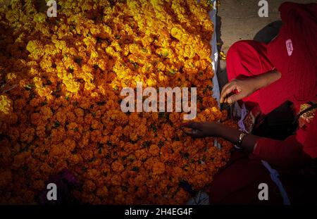 Kathmandu, Bagmati, Nepal. 2 novembre 2021. Una donna prepara la ghirlanda di fiori marigold durante il festival di Tihar in un mercato a Kathmandu, Nepal il 2 novembre 2021. Tihar o Diwali, la festa indù dei fiori e delle luci, è celebrata per cinque giorni. (Credit Image: © Sunil Sharma/ZUMA Press Wire) Foto Stock