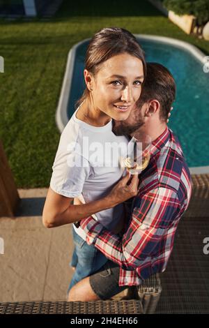 Donna attraente che guarda la fotocamera mentre si gode la giornata di sole con il suo uomo in campagna Foto Stock