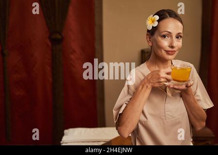 Cliente salone di bellezza calmo con bevanda a base di erbe in posa per la macchina fotografica Foto Stock