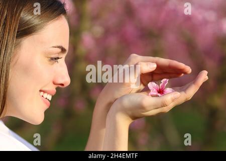 Profilo di una donna felice che protegge il fiore nelle sue mani in un campo Foto Stock