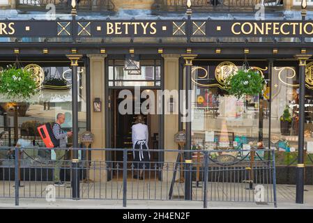 Bettys Harrogate, vista posteriore di una cameriera che ritorna all'interno del Bettys Cafe and Tea Rooms su Parliament Street, Harrogate, North Yorkshire, Inghilterra, Regno Unito Foto Stock