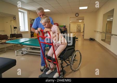 Fisioterapista professionista assiste la paziente in guarigione al centro di riabilitazione Foto Stock